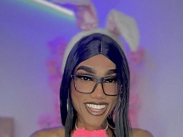 Arlinx with long black hair, glasses, and a white bunny ear headband, smiling, has dark skin, pink furry collar, and is showing off her shiny white teeth.