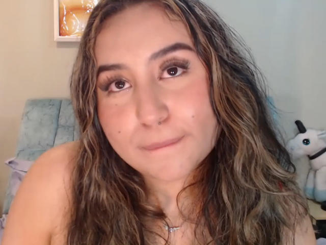 SalomettX ha i capelli castano ondulati, un piercing al naso ed è sorridente, con lunghe ciglia. Sta guardando la fotocamera con un leggero sorriso, carino. Il suo seno non è visibile..