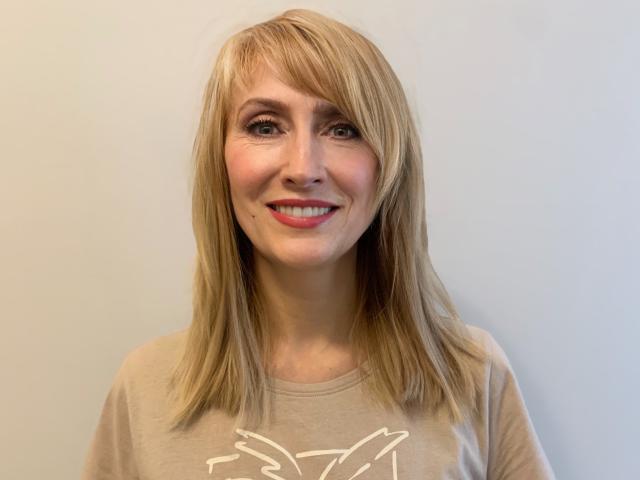 MargaretPretty69 has blonde hair, light skin, and a cute smile with pink lipstick. She's wearing a beige shirt with a white graphic, looking happy and relaxed.