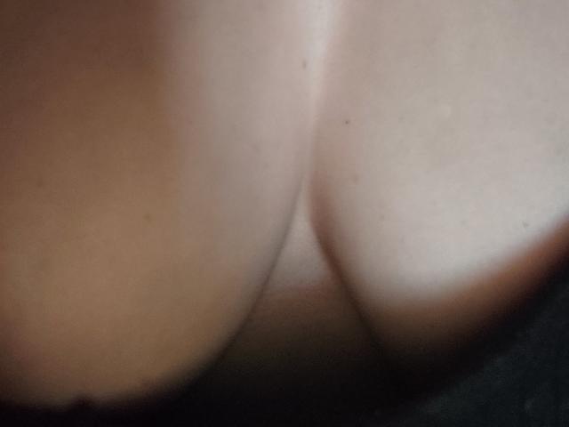 Les gros seins pâles et nus de LinnaLove sont serrés l'un contre l'autre, révélant une peau lisse et crémeuse avec de légères marques de bronzage. L'image est très rapprochée, en gros plan et légèrement floue..