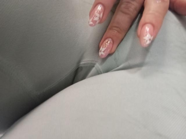 La mano di Christine Bray, con le sue unghie decorate in rosa e bianco, riposa sul suo sedere bianco. Le sue dita sono leggermente incurvate, mettendo in risalto le sue unghie curate..