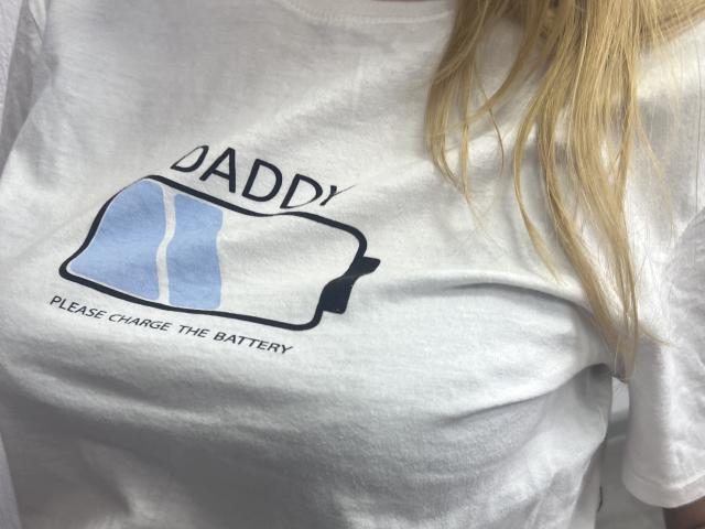 Laliina's white t-shirt with a blue battery graphic and text, showing her small tits and blonde hair, is visible in the photo.