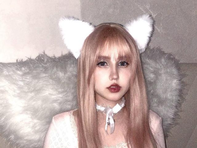KaylaWow with white cat ears, pink hair, and fluffy gray wings, wearing a white lace choker and pink dress, has red lips and a cute, innocent face.
