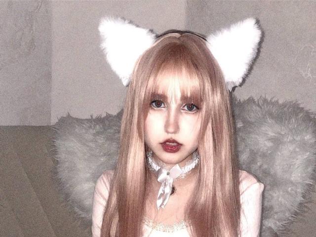 KaylaWow with long blonde hair, white furry cat ears, and a white choker, has small tits and red lips, looking at the camera with a cute, innocent expression.