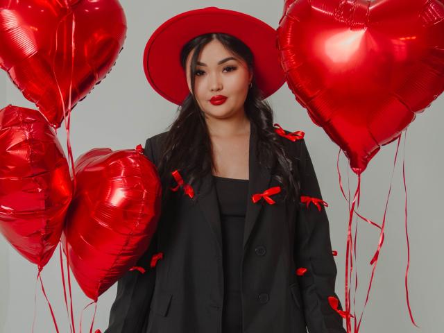 TeyaFaber with red heart balloons, wearing black outfit, red hat, and red lipstick, holding red heart balloons, black hair, cute, sexy, medium tits, white background, red ribbons.