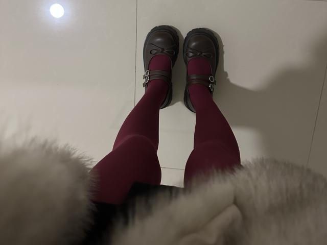 LaraSweetyHot's legs in red tights, wearing black leather Mary Jane shoes with buckles, standing on white tile floor, shadow on right, with fluffy white texture in bottom left.