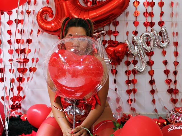 Sexy vrouw met een rode ballon voor haar gezicht, gekleed in rode lingerie en hoge kniehoogte kousen, die een rode hartvormige ballon vasthoudt, omringd door rode ballonnen en hartdecoraties..
