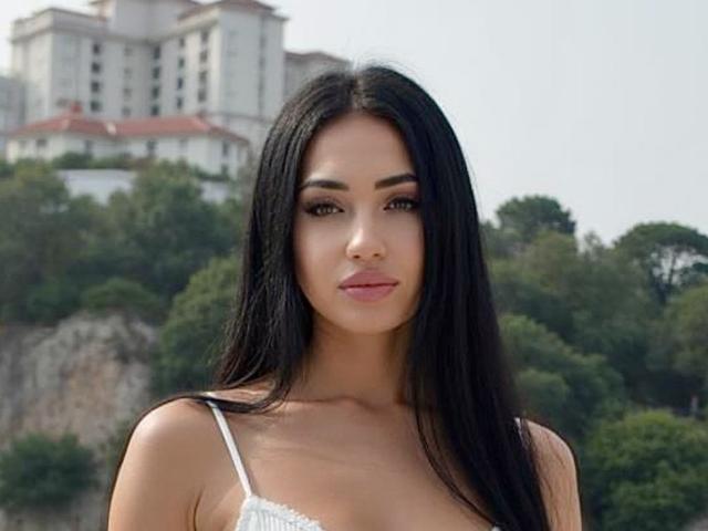 AlisonCindy has long black hair, brown eyes, and wears a white lace bra, showing her small tits, with a slightly tanned, pretty face and pink lips, looking forward.