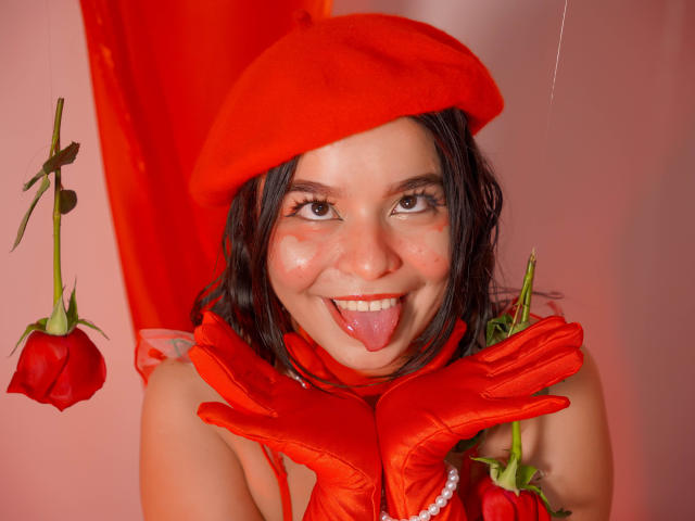 LissyCarter with red hat, gloves, and roses, sticking out tongue, has freckles, dark wet hair, and is wearing a red scarf with a pearl necklace.