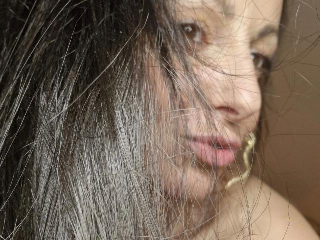 LuderMeggie-hot's face is partially obscured by her long, straight, gray-black hair. She has brown eyes, pink lips, and is wearing a gold hoop earring on her right ear.