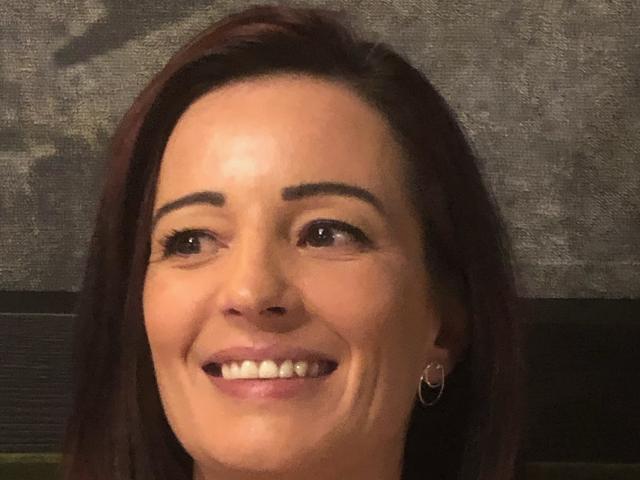NinaSensuelle has a smiling face with brown eyes, dark eyebrows, straight red hair, and small hoop earrings, showing white teeth. Her skin is light and she's wearing pink lipstick.