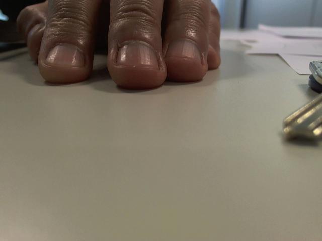 Olegator-hot's hand with fingers pressed against a smooth, beige surface, showing slightly dirty, short nails and a small cut on the index finger.