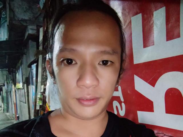 NaughtySexFrYou has a serious face with brown eyes, slightly parted lips, and a small nose. They're wearing a black shirt, and their hair is tied back.