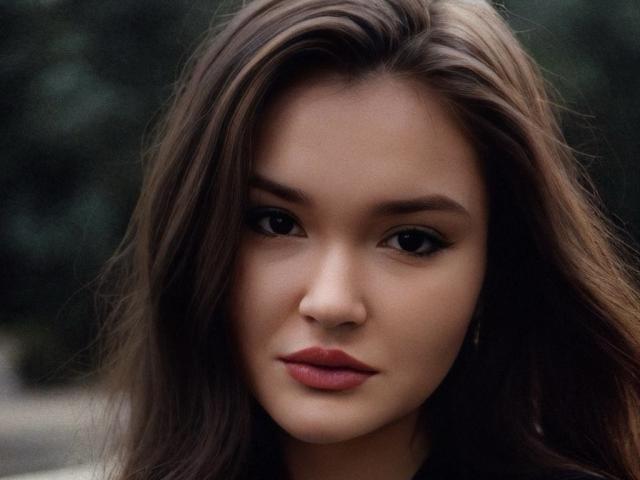 EvaLacroix has long brown hair, full lips with red lipstick, and dark, slightly almond-shaped eyes. She looks serious with a soft, smooth complexion. Boobs aren't visible.