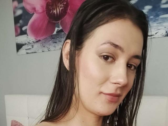 JuliaHuntis has straight dark brown hair, brown eyes, and a slight smile. She's showing a small zit on her right cheek. Her boobs are not visible.