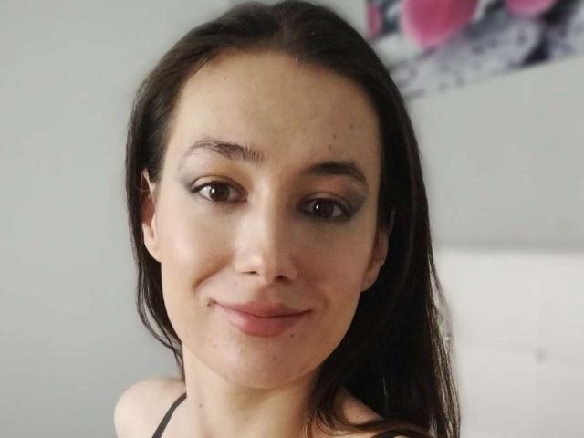 JuliaHuntis has a cute face with brown eyes, dark brown hair, and a slight smile. Her small tits are barely visible under a black halter top.