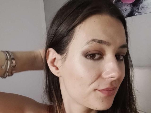 JuliaHuntis has light skin, brown eyes, and dark brown hair, with a slight smirk, wearing bracelets on her right arm, and a small nose piercing.