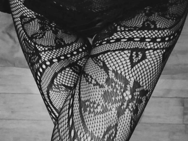 MagLena's black lace fishnet legs with intricate floral patterns, showing her thighs and a small part of her ass. The texture is tight and sexy.