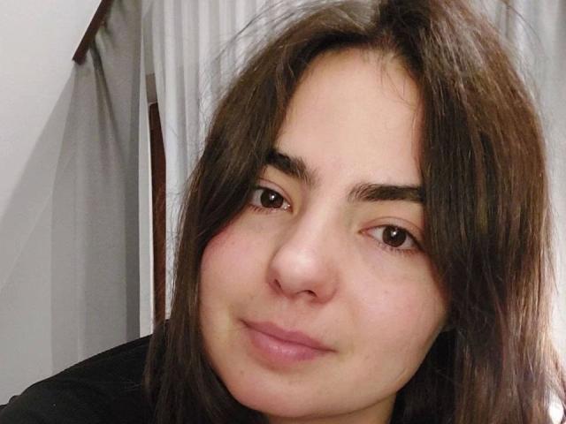 DeniseLove-hot tem cabelos castanhos de comprimento médio, olhos castanhos e um sorriso discreto. Seu nariz é pequeno e ela está vestindo uma camisa preta. Sua pele é clara..