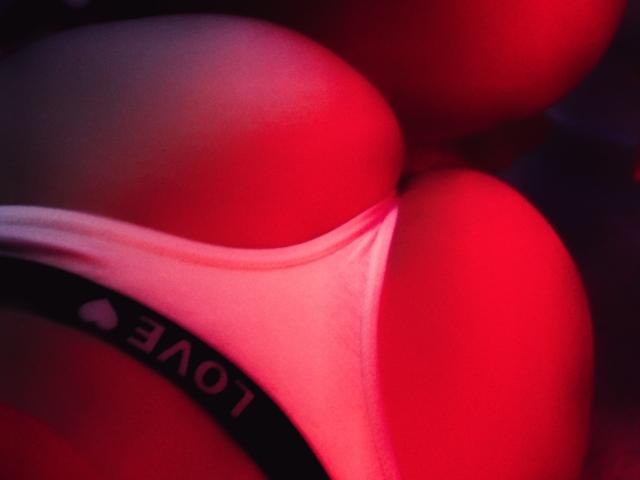 LilithInTheEdenX's butt in white panties, highlighted by red lighting, with a black waistband that has white text. Focus on her round, smooth, and slightly curved buttocks.