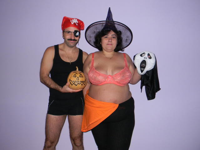 Keyx with a red pirate hat and eyepatch, holding a pumpkin, next to Keyx with a witch hat, pink lace bra, orange scarf, and white mask.