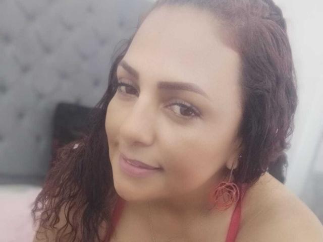 Helen Walker tem cabelos cacheados castanho-escuros, olhos castanhos e um tom de pele claro. Ela está sorrindo, usando batom rosa, brincos vermelhos e uma blusa vermelha. Os seios estão parcialmente visíveis..