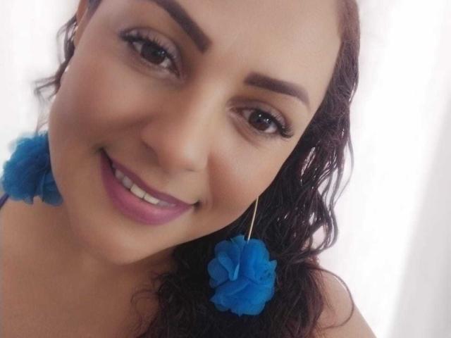 El rostro de Helen Walker, con cabello castaño oscuro ondulado, aretes con forma de flores azules y una sonrisa encantadora. Tiene ojos marrones, lápiz labial rosa y un tono de piel claro. Sus senos no son visibles..