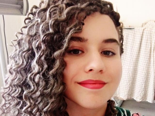 MarlanViviane has curly gray and black hair, red lipstick, and a cute smile, with a light skin tone and small nose. She's looking at the camera with brown eyes.
