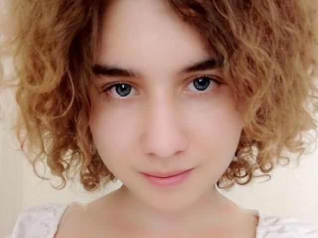 MarlanViviane has curly brown hair, blue eyes, and a slight smile. She's looking directly at the camera with a soft, cute expression. Her tits are not visible.