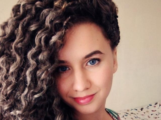 MarlanViviane has curly brown hair with blonde highlights, blue eyes, pink lipstick, and a slight smile. Her face is slightly turned, showing off her left side profile.