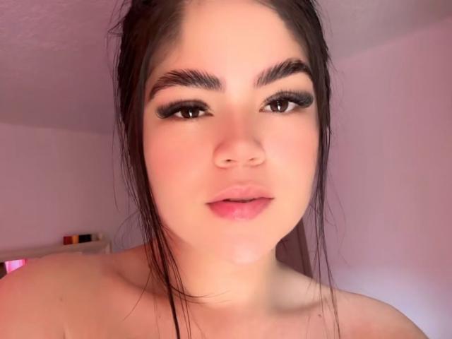 MartinaRossyI has dark, wet hair, thick eyebrows, long eyelashes, and pink lips. She's topless with fair skin and a slightly flushed face. The photo is a selfie.