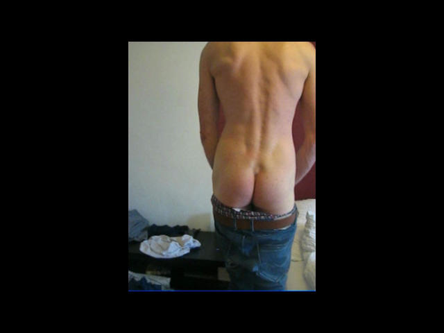 Shirtless Defender-hot with a muscular back, blue jeans pulled down to reveal bare ass, standing in a room with clothes on a table.