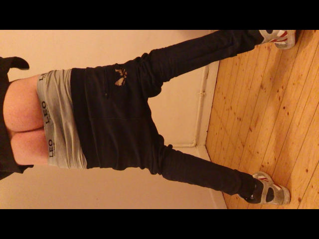 Defender-hot's ass in tight grey underwear, black ripped jeans, and white sneakers, standing with legs apart, wearing a black top, in a wooden room.