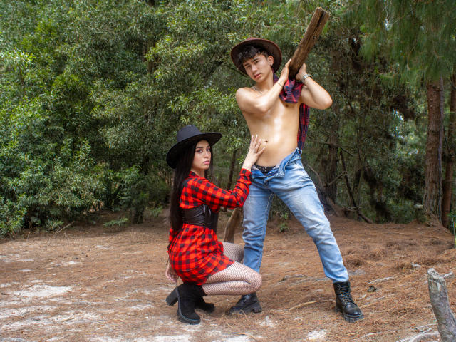 Noah e Rose, sem camisa, vestindo jeans e chapéu, seguram um bastão de madeira, enquanto Rose, em um vestido xadrez vermelho, chapéu preto e meia-calça, toca o abdômen de Noah em uma floresta. O pênis de Noah não está visível..