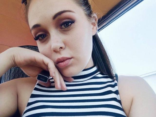 IziPaterson has a cute face, dark brown eyes, and is wearing a black and white striped sleeveless top, resting her chin on her hand with a black ring.