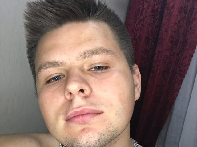 MagicH tiene una cara redonda con cabello corto y puntiagudo de color marrón, ojos azul claro y un pequeño bigote ralo. Está sin camisa y tiene una expresión ligeramente fruncida y neutra..