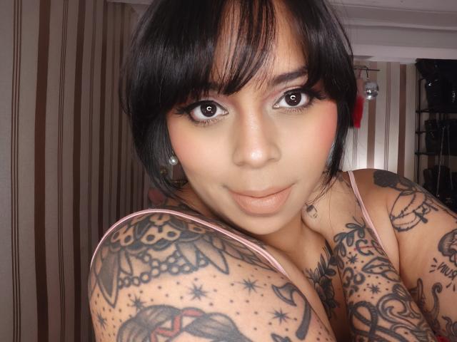 Chili ha enormi tatuaggi sulle tette, capelli scuri e grandi occhi marroni, sembra sexy con un sorriso, braccia piene di inchiostro intricato.