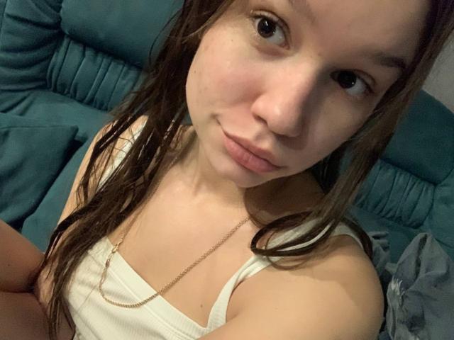 MisaQueen has wet brown hair, light skin, small tits in a white tank top, and a subtle smile, looking up at the camera with a slight gaze.