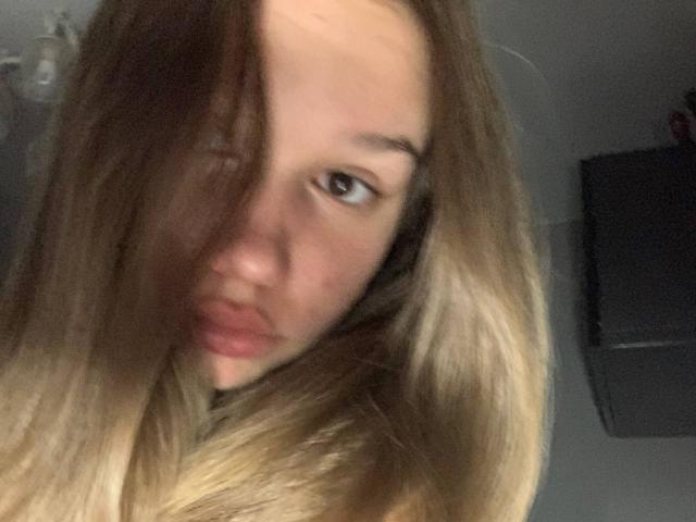 MisaQueen a de longs cheveux bruns et blonds qui lui couvrent un œil, des lèvres roses et pulpeuses, et un selfie légèrement flou en gros plan qui montre ses yeux bruns et sa peau pâle..