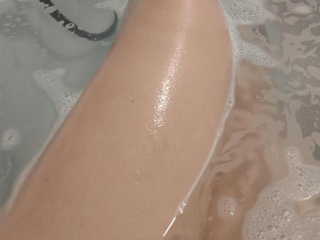 KimStar's wet, glistening butt in a bubbly bathtub, with foam partially covering her smooth, pale skin. The focus is on her rounded, shiny buttocks.
