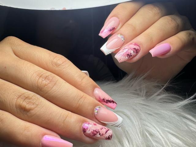 CelesteRusso's pink and white manicured nails with black floral patterns and diamond tips, showing off her French tips and pink polish on her fingers resting on a white fur.