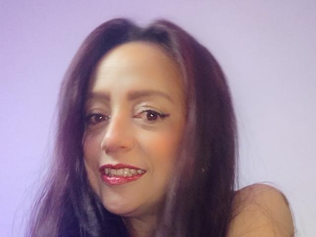 CatalinaMonyque has long dark brown hair, red lipstick, and a nose ring, smiling with slightly visible teeth, and brown eyes in a soft-lit, blurry selfie.