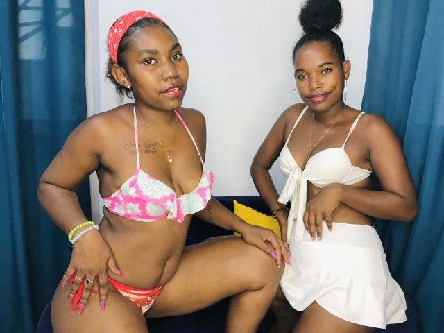 StellaTruda on the left with pink floral bikini, red panties, and headscarf, showing her tits and ass. StellaTruda on the right in white strapless top and skirt.