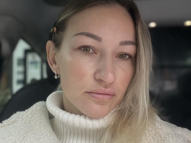 Lilitraya with light skin, green eyes, and blonde hair in a side part, wearing a white turtleneck, has a small star hair clip and a subtle nose ring.