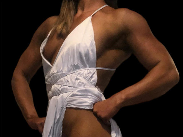 muscular lolacarrera-hot in a white, deep-cut dress, showing strong arms and a slanted side view of her tits and flat, toned stomach, holding the dress up slightly.