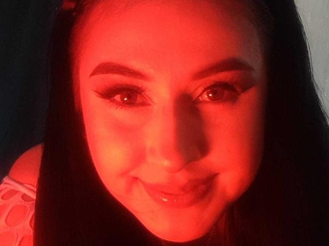 Het gezicht van FrancheskaaWaalsh is rood, met lang zwart haar, dikke wenkbrauwen en volle lippen die lichtjes glimlachen. Ze heeft eyeliner en haar ogen kijken vooruit..