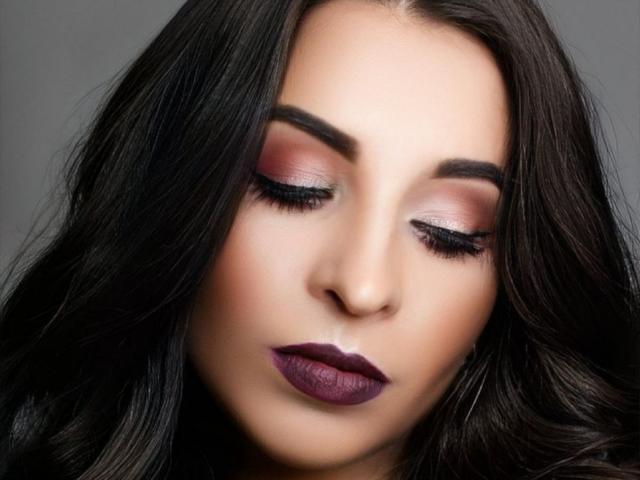 GabriellaSun's face with dark, wavy hair, closed eyes, pink and purple eyeshadow, long eyelashes, and deep purple lipstick. Smooth, fair skin. Pretty, sexy, attractive.