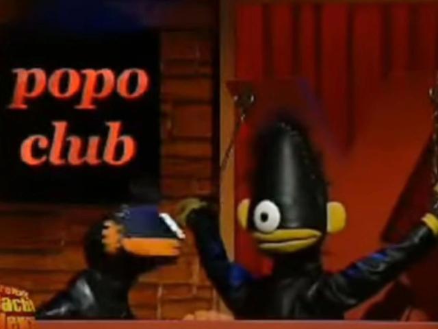 Two Voennies-hots in black, shiny suits with orange beaks and yellow noses, arms raised, in a club setting. One has a blue cap. The other has a raised arm.