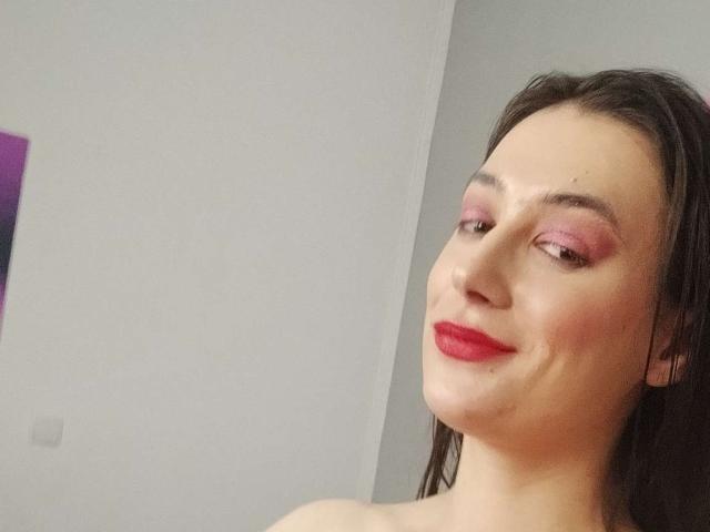 JuliaHuntis with pink eyeshadow, red lipstick, and wet brown hair, smiling at the camera. Her face is slightly turned with a cute, confident expression. Boobs not visible.