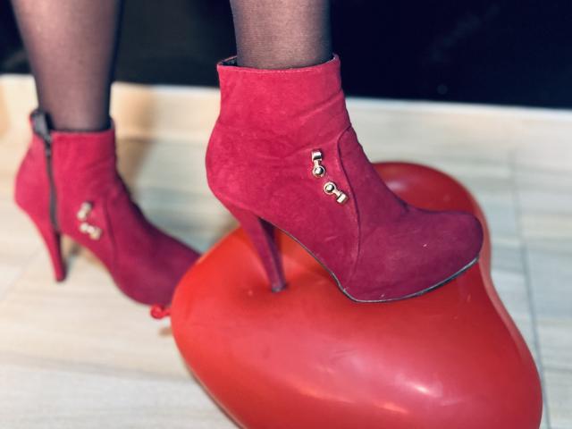 SilenaLee's red suede ankle boots with gold buttons are on her black panty legs, standing on a red heart-shaped stool with high heels.